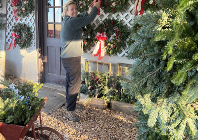 Laura hanging up our array of holiday wreaths